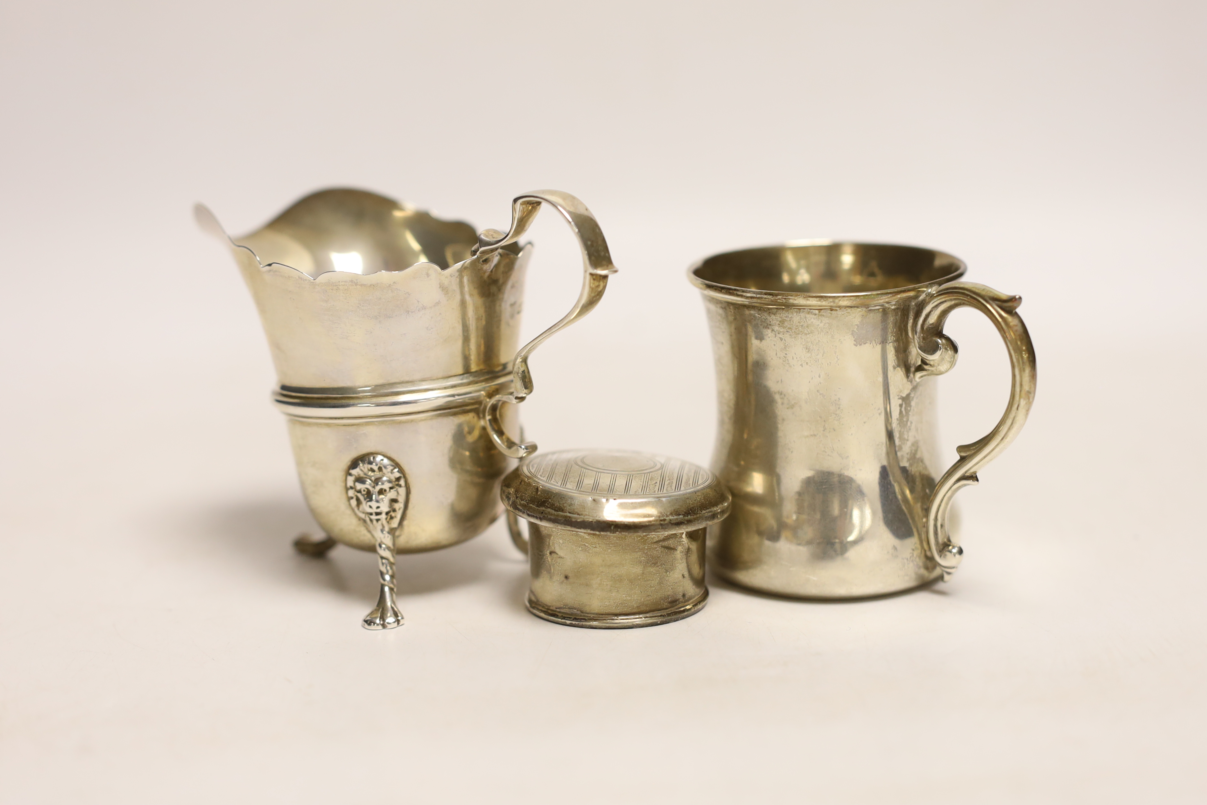 A George V silver cream jug, Goldsmiths & Silversmiths Co Ltd, London, 1921, 82mm, a small silver mug and a silver scent bottle top.
